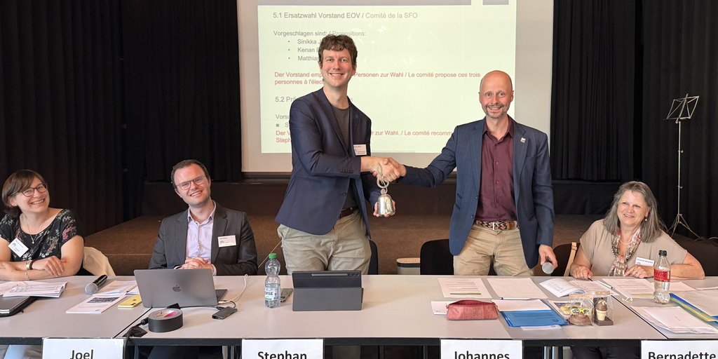 Der abtretende EOV-Präsident Johannes Reinhard übergibt die EOV-Glocke an der DV 2026 in Rapperswil an seinen Nachfolger Stephan Matter.