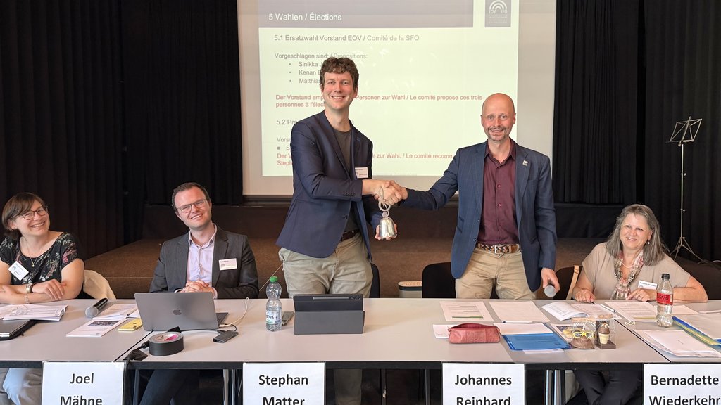 Der abtretende EOV-Präsident Johannes Reinhard übergibt die EOV-Glocke an der DV 2026 in Rapperswil an seinen Nachfolger Stephan Matter.