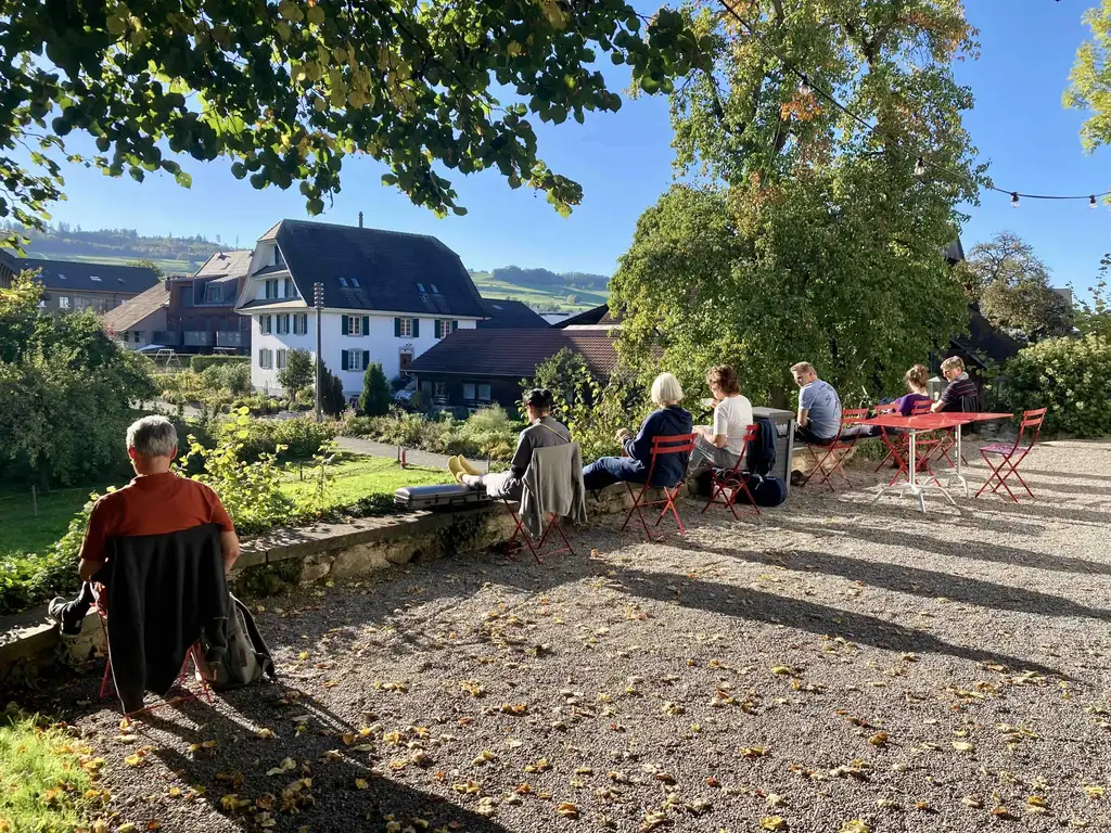 Idyllische Umgebung: Teilnehmende der Boswiler Orchesterakademie für Amateurmusiker:innen entspannen im Jahr 2022 während einer Probenpause vor der Alten Kirche.